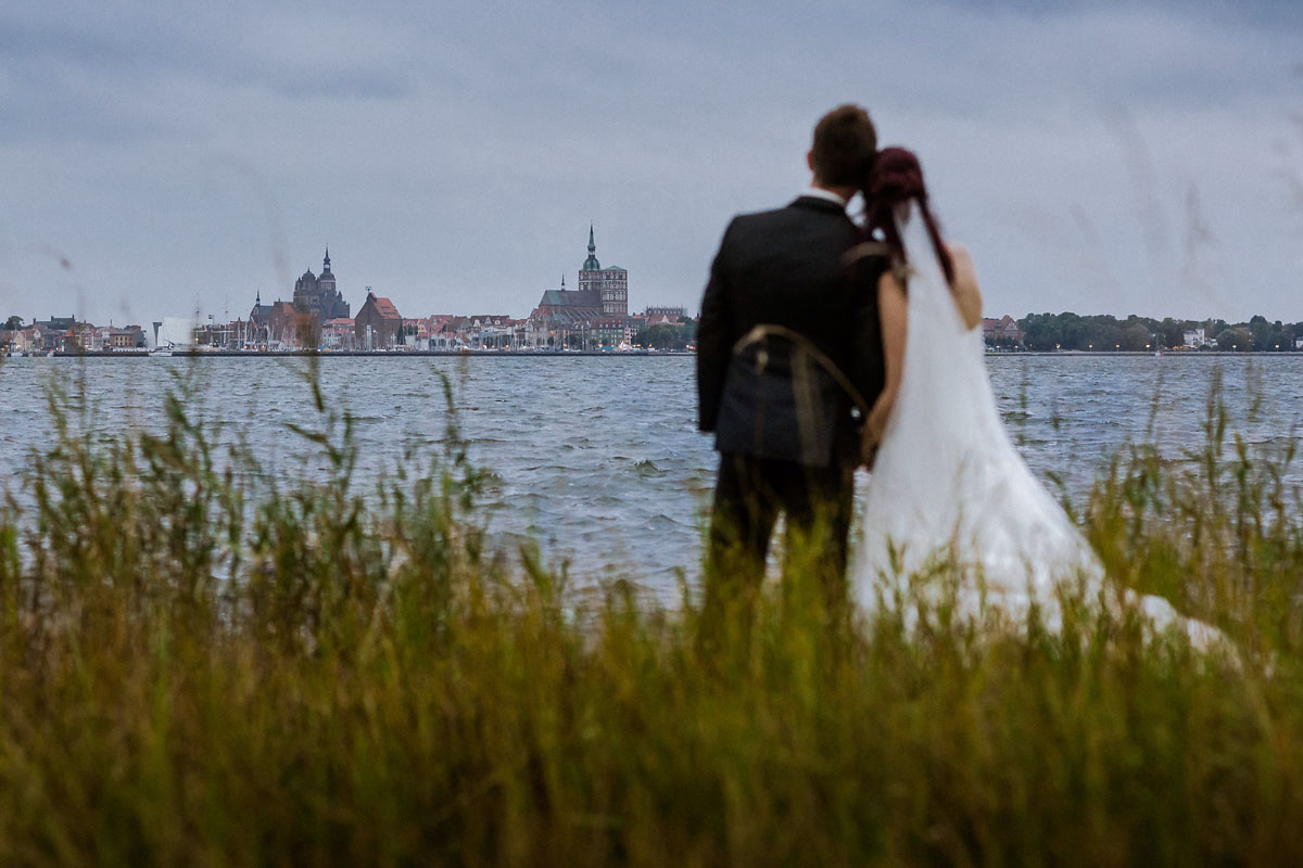 Brautpaar blickt von Altefaehr auf Stralsund Hochzeitsfotograf © www.henninghattendorf.de