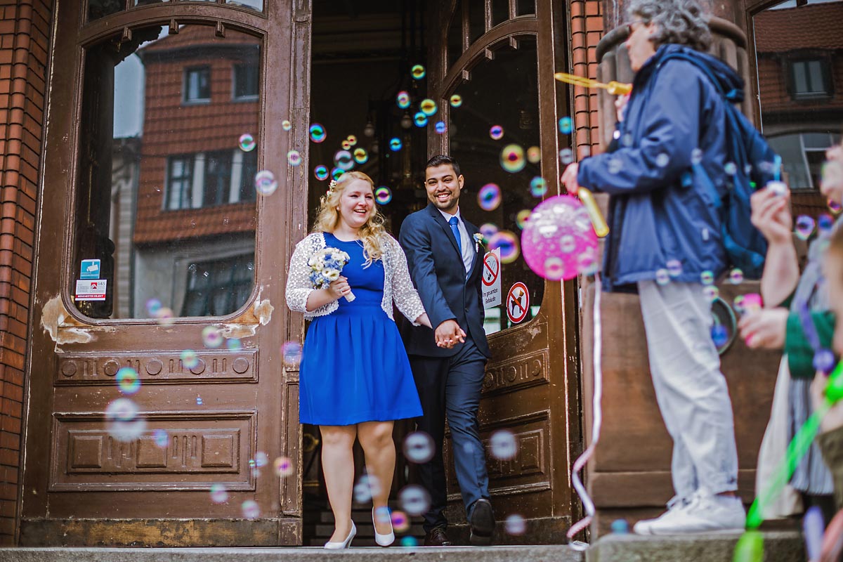 Hochzeitspaar wird mit Seifenblasen an der Tür vom Standesamt Pankow in Berlin empfangen Hochzeitsfotograf © www.henninghattendorf.de