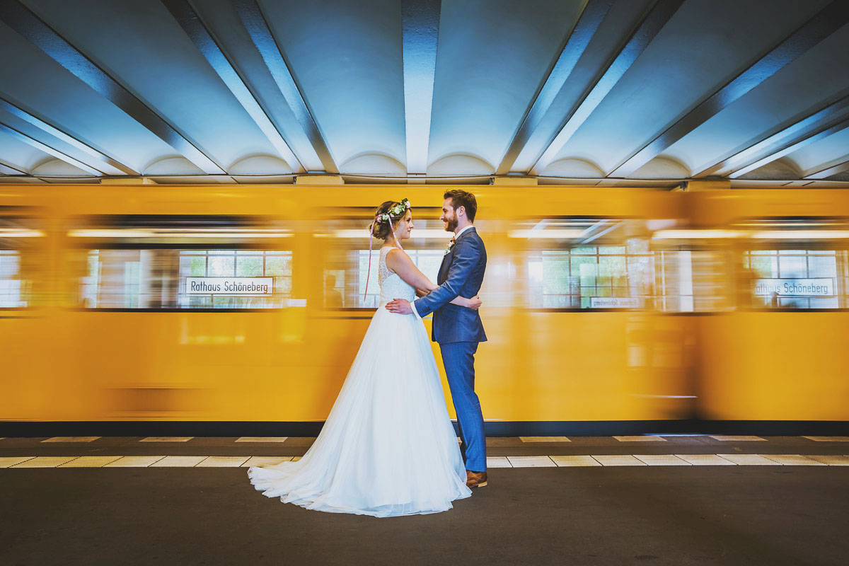 Brautpaar und einfahrende U Bahn im U Bahnhof Rathaus Schöneberg in Berlin Hochzeitsfotograf © www.henninghattendorf.de