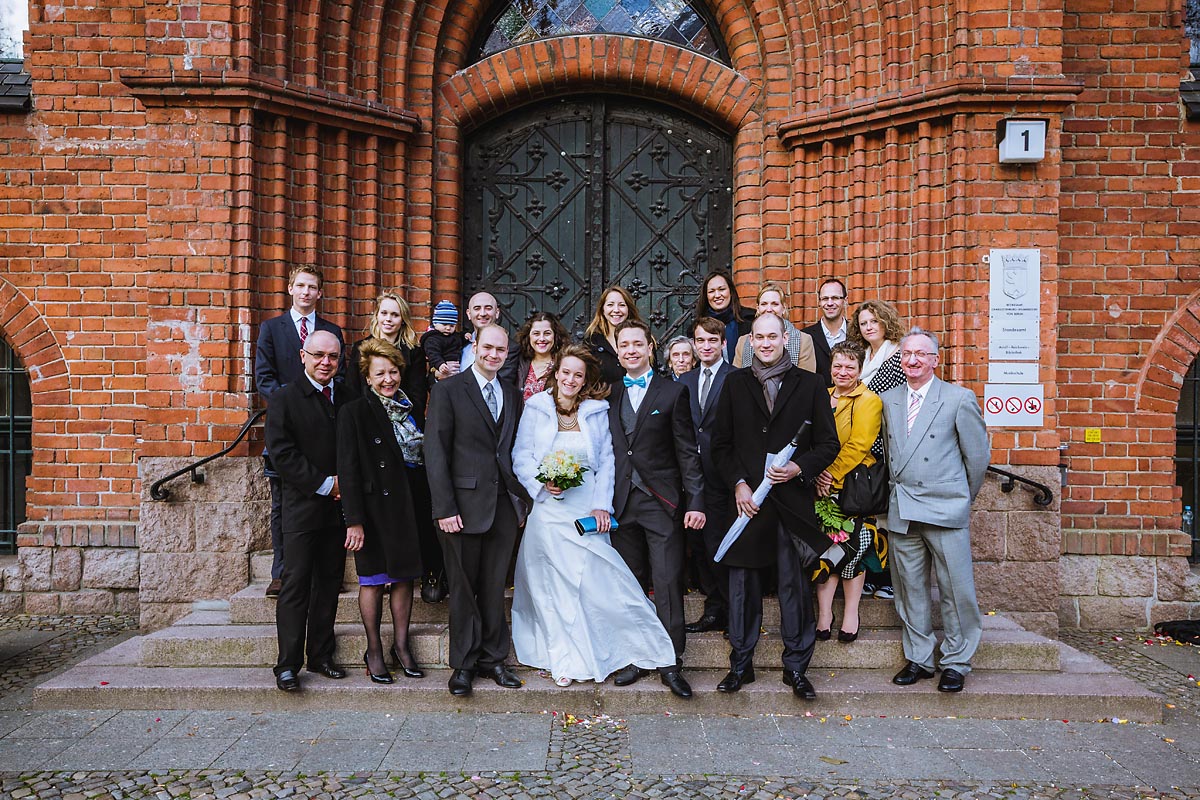 Gruppenfoto der Hochzeitsgesellschaft an der Tür zum Standesamt Schmargendorf in Berlin Hochzeitsfotograf © www.henninghattendorf.de